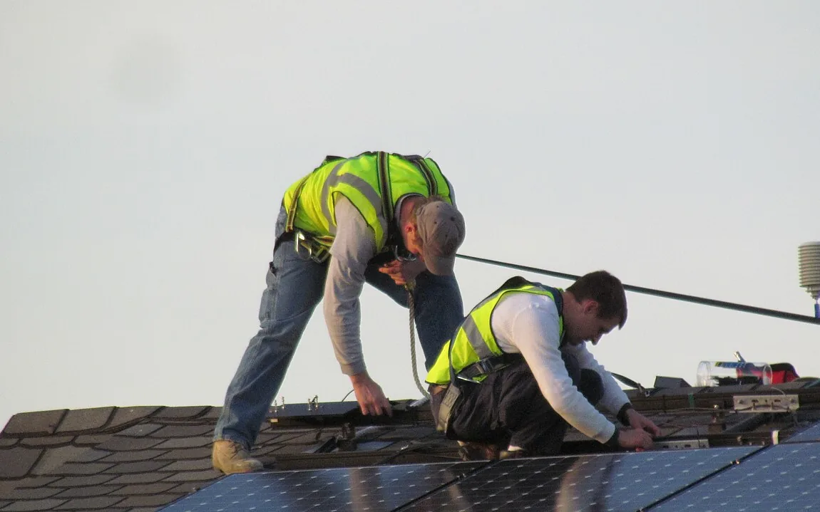 Deux techniciens installent des modules photovoltaïques sur une toiture